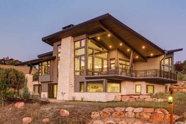 Back of house featuring a balcony and stone siding