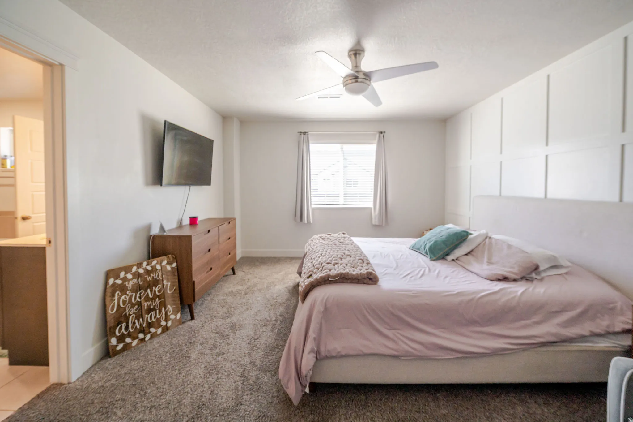 Bedroom with ceiling fan, light colored carpet, a textured ceiling, and ensuite bath