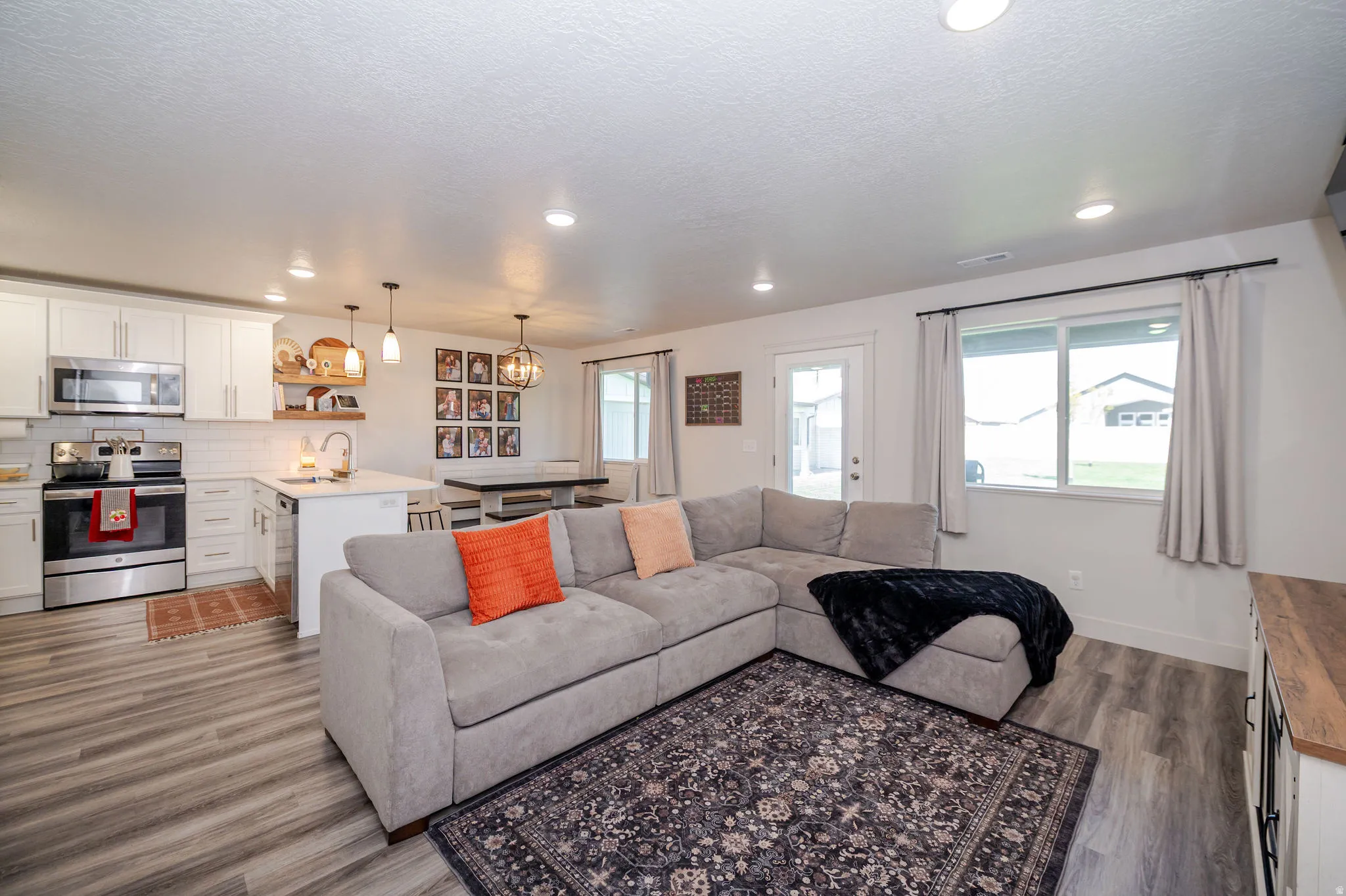 Living area featuring dark wood-type flooring, hanging lights, and a textured ceiling