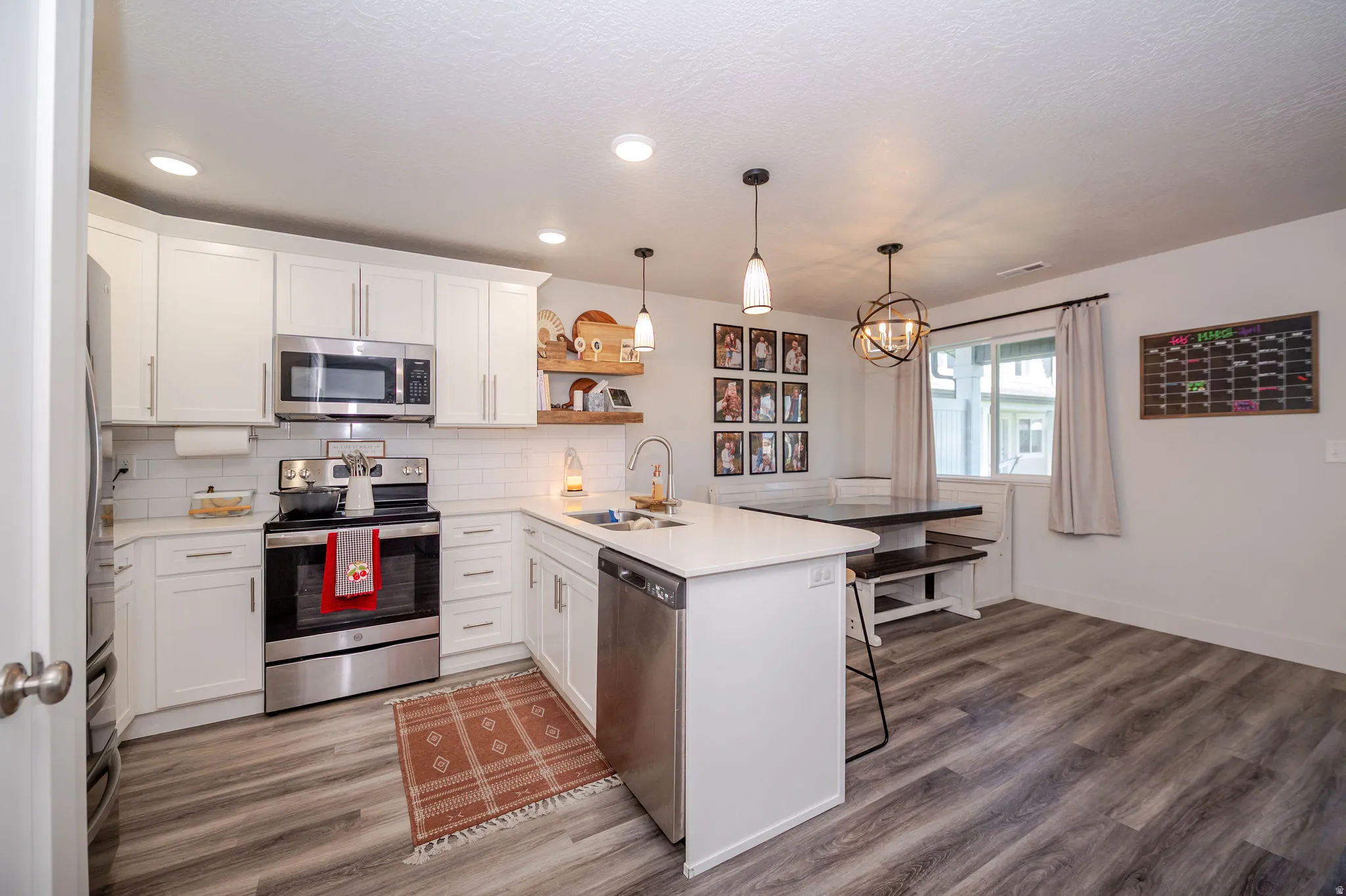 Kitchen featuring a peninsula, stainless steel appliances, white cabinets, and a kitchen breakfast bar
