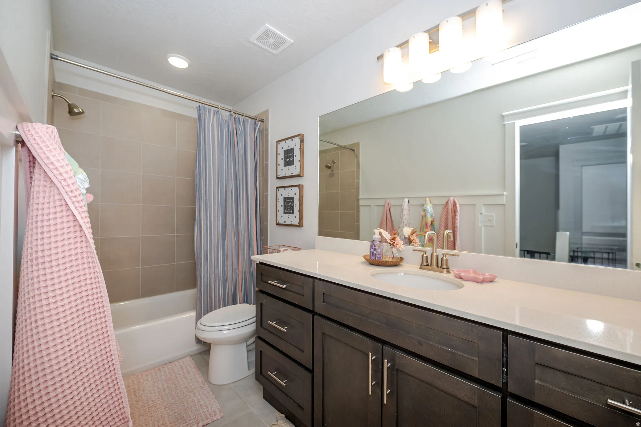 Full bathroom featuring vanity, shower / bath combo with shower curtain, and light tile patterned floors