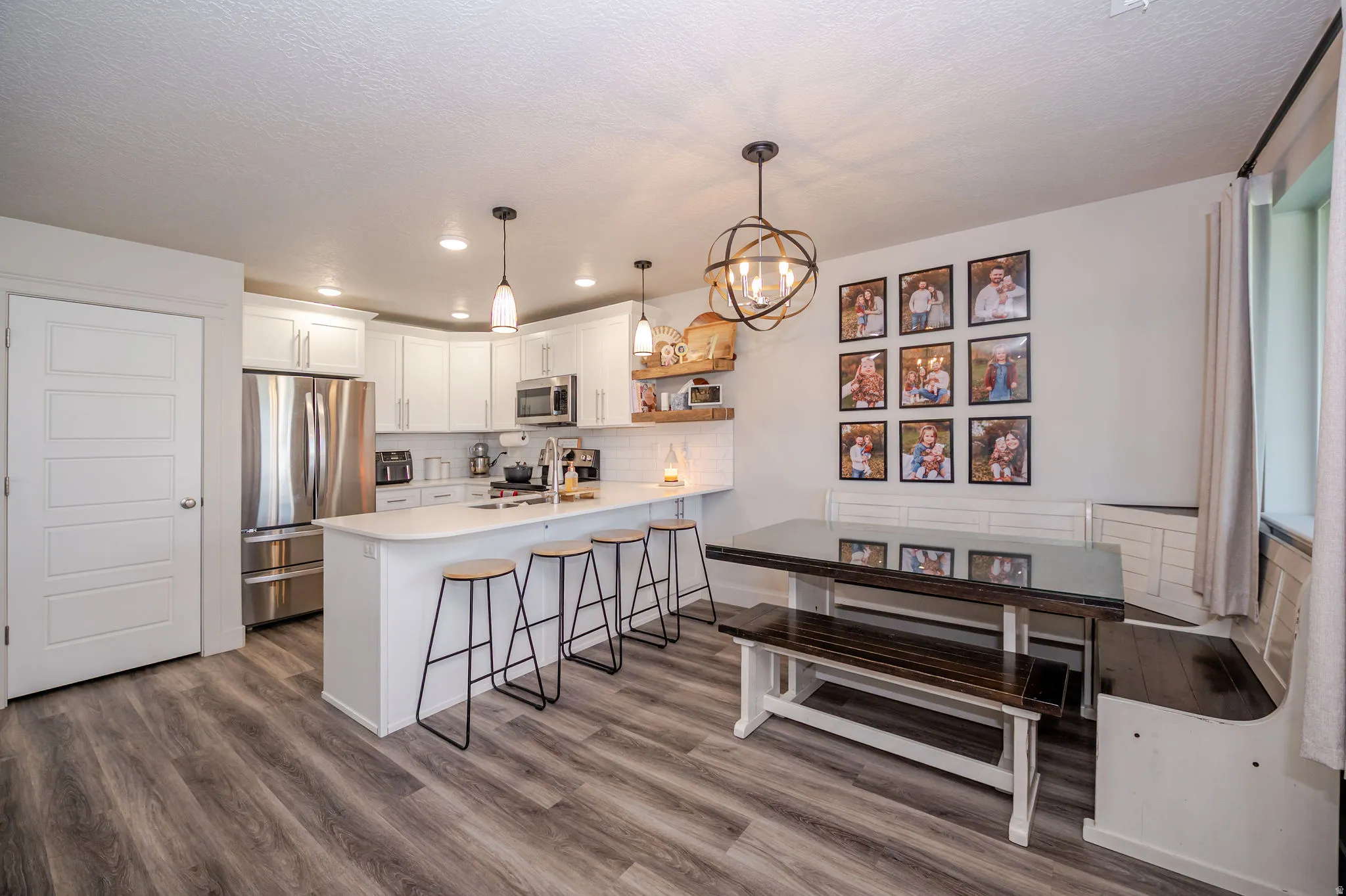 Kitchen featuring stainless steel appliances, a peninsula, white cabinets, a breakfast bar, and a chandelier