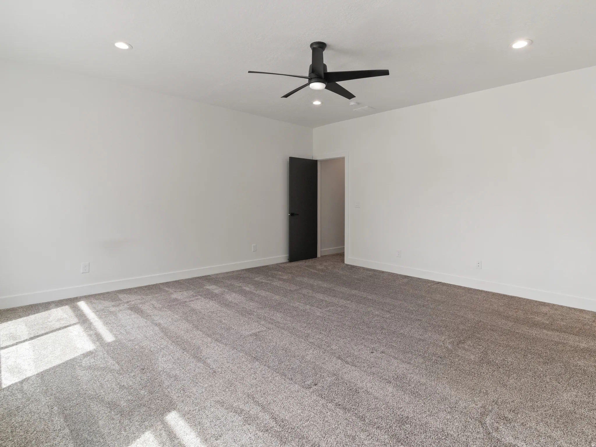 Carpeted empty room with a ceiling fan and recessed lighting