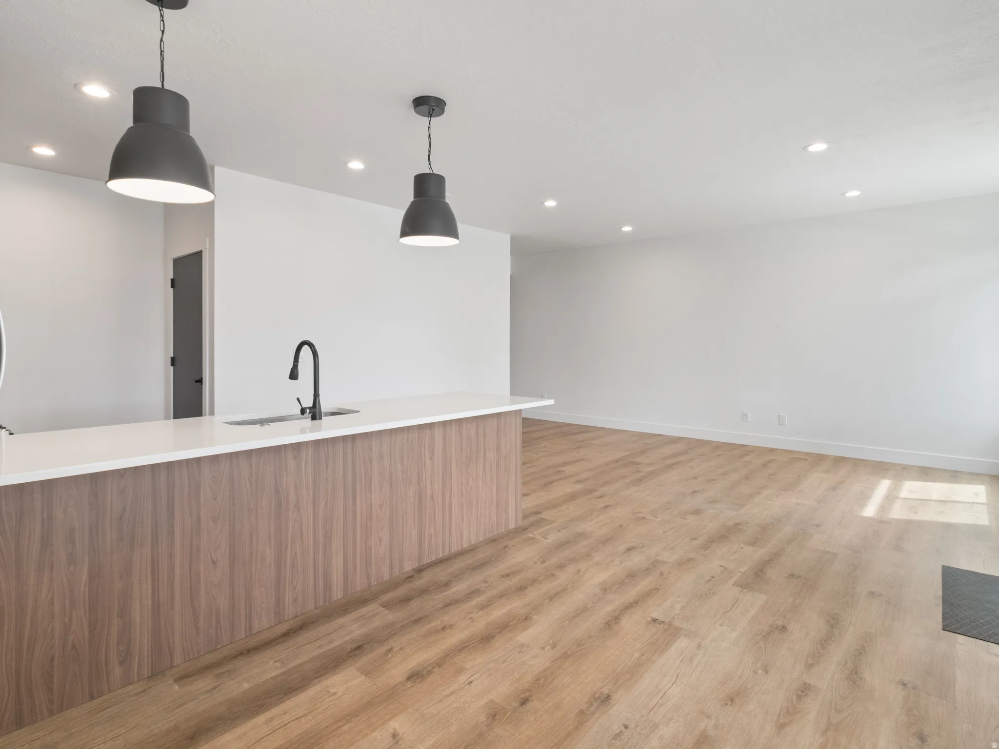 Kitchen with modern cabinets, light wood-style flooring, pendant lighting, light stone countertops, and wood finish cabinetry