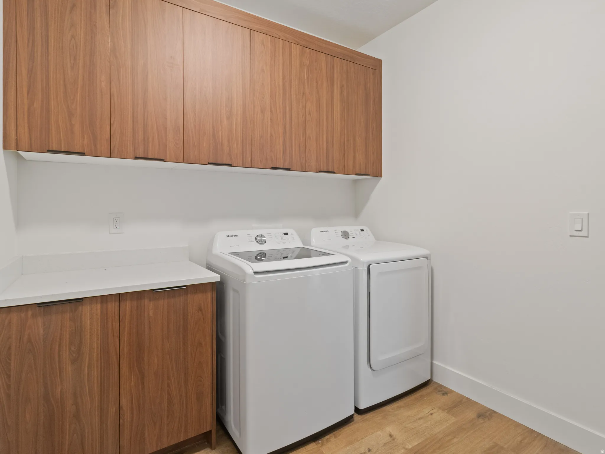 Laundry area with light wood-type flooring, separate washer and dryer, and cabinet space