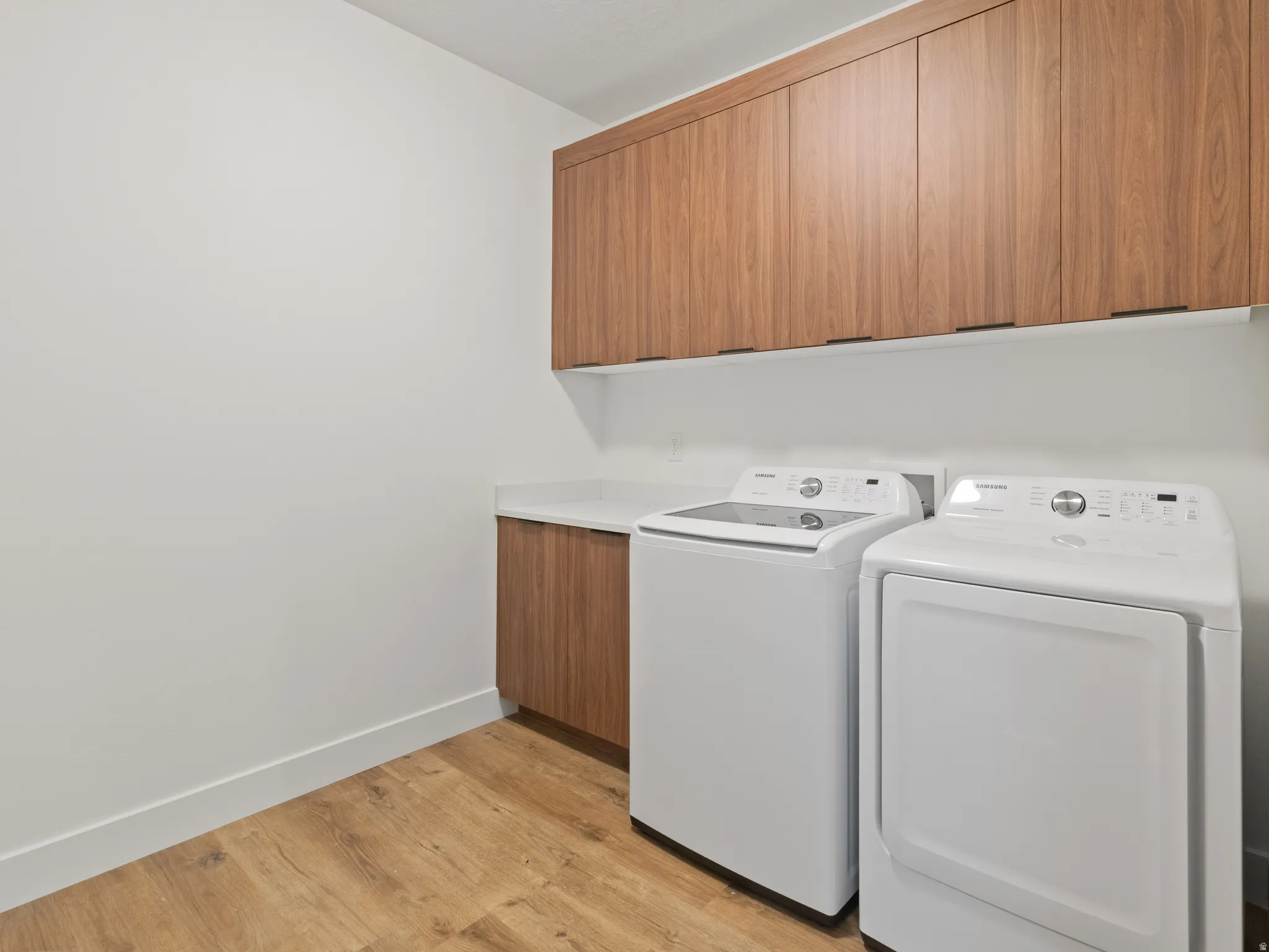 Laundry room with light wood-style flooring, independent washer and dryer, and cabinet space