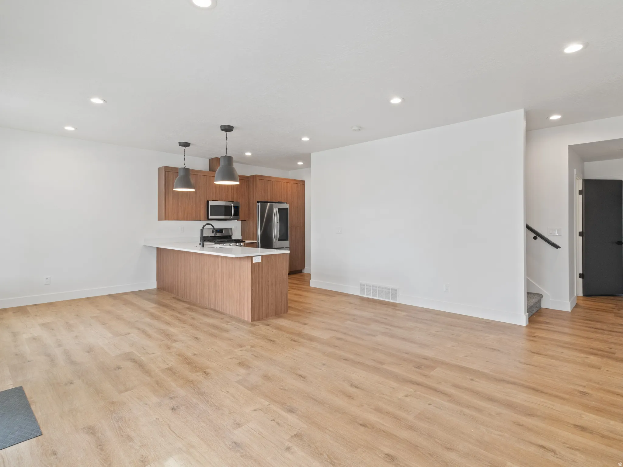 Kitchen with wood finish cabinets, hanging light fixtures, open floor plan, and a peninsula
