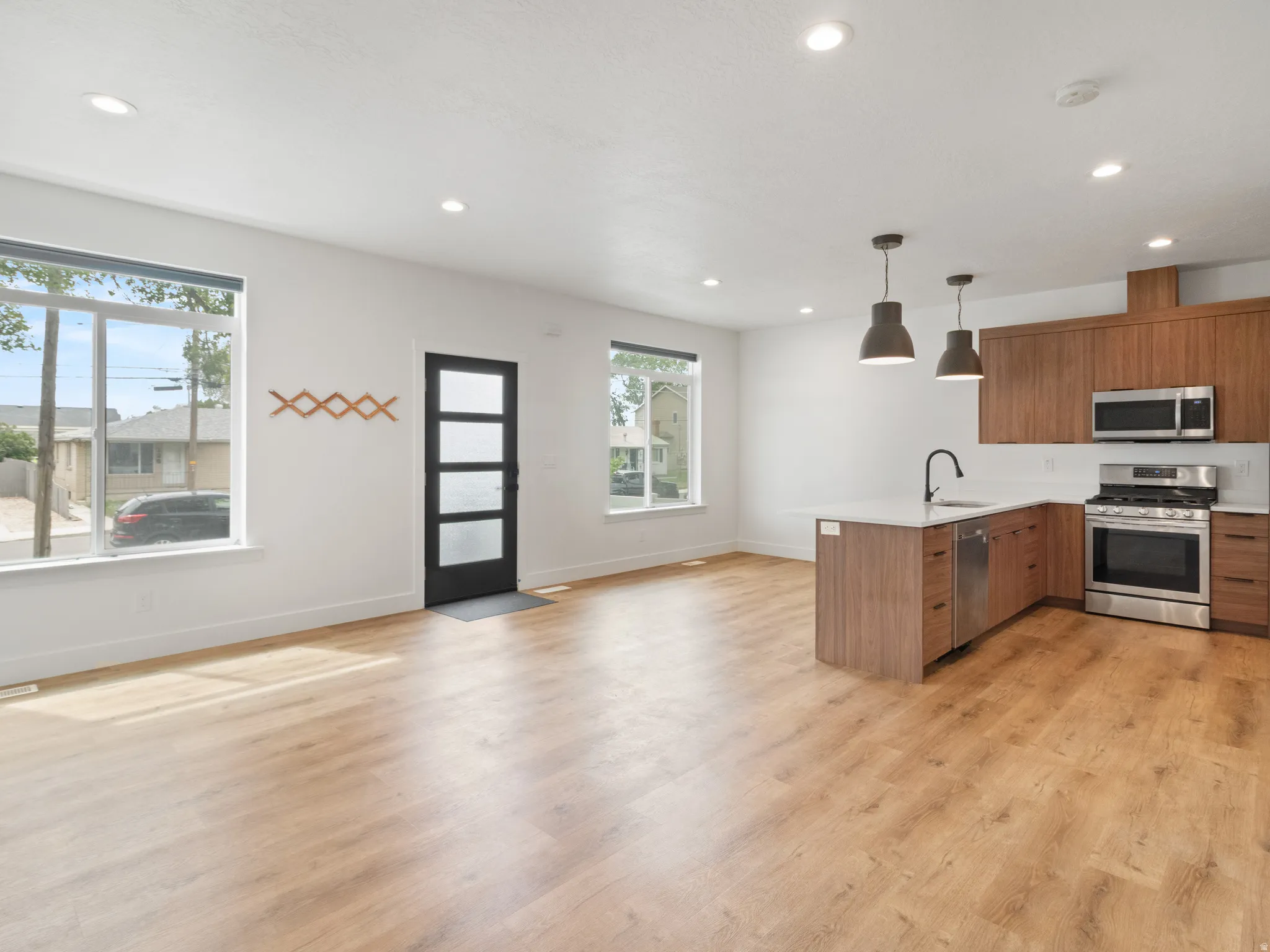 Kitchen featuring pendant lighting, open floor plan, stainless steel appliances, wood finish cabinetry, and a peninsula