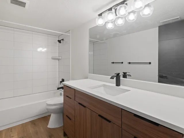 Full bathroom with vanity, bathtub / shower combination, dark wood finished floors, and a textured ceiling