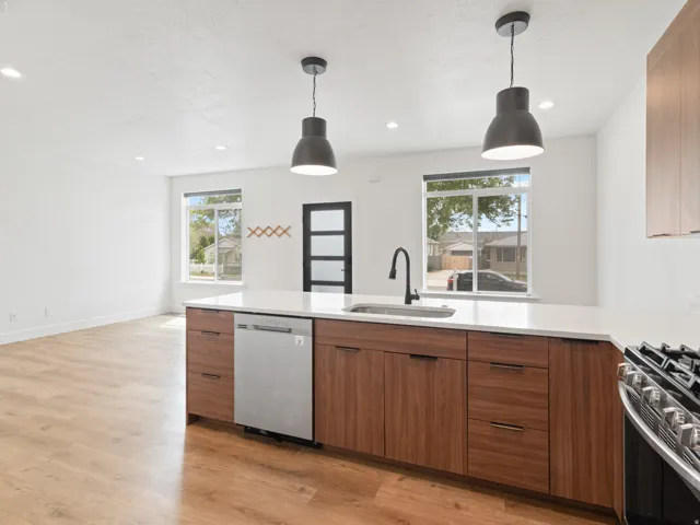 Kitchen with stainless steel appliances, wood finish cabinetry, light wood-type flooring, and hanging light fixtures