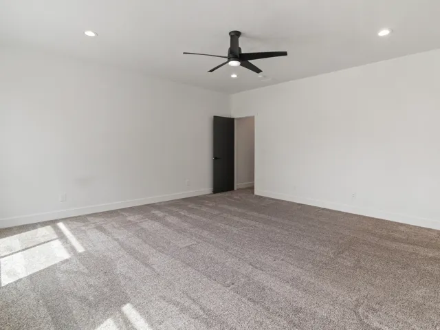 Carpeted empty room with a ceiling fan and recessed lighting