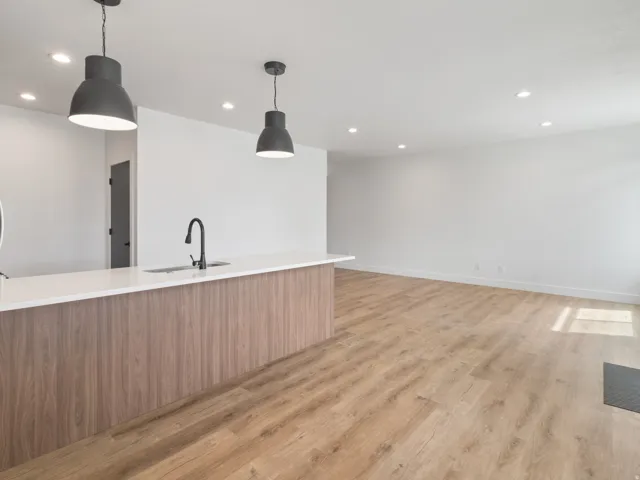 Kitchen with modern cabinets, light wood-style flooring, pendant lighting, light stone countertops, and wood finish cabinetry