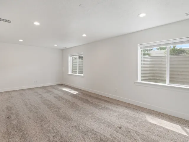 Empty room with light carpet, plenty of natural light, and recessed lighting