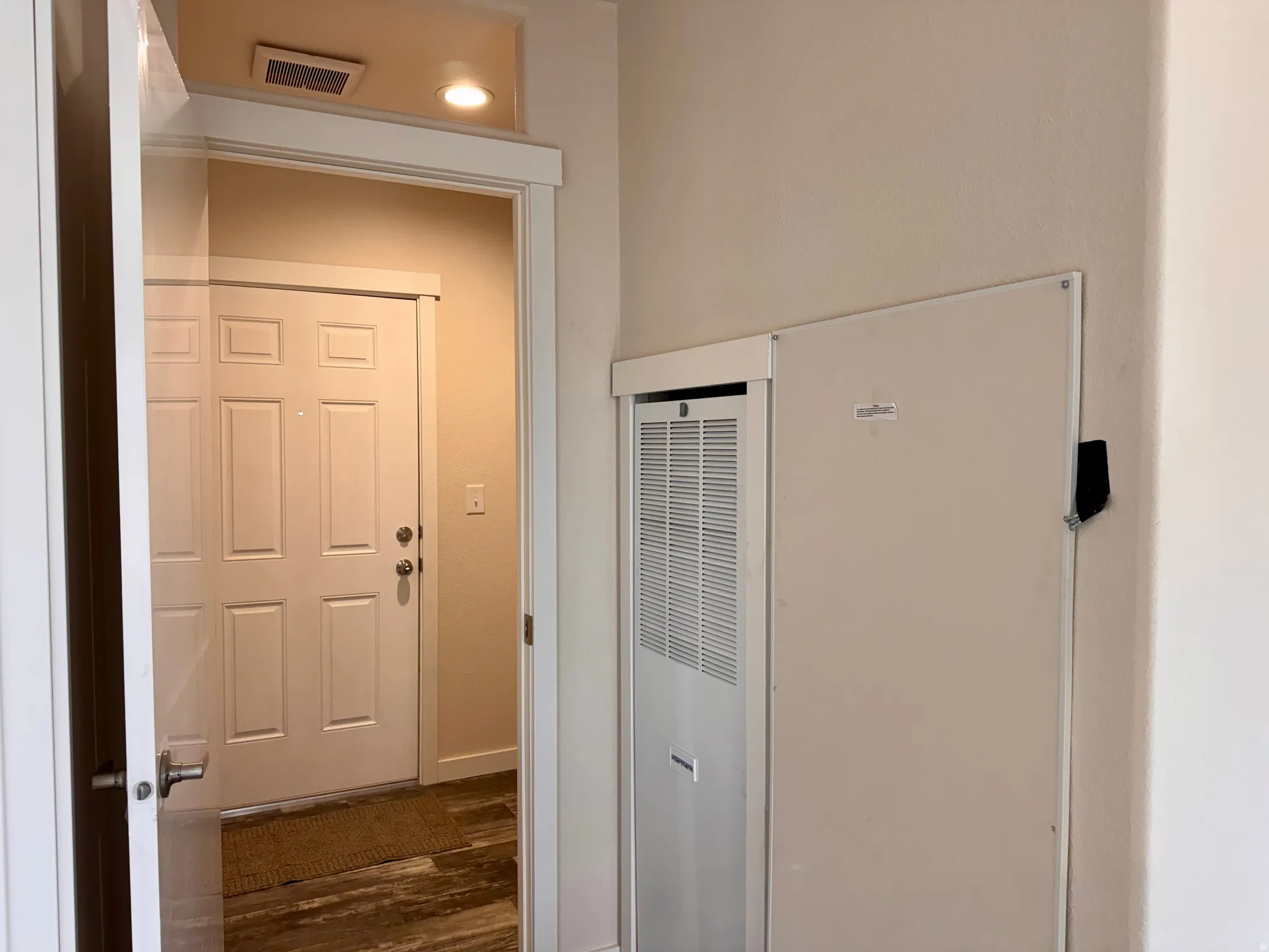 View of back door and laundry area from the hallway. Includes forced air electric furnace that is not currently not being used. Currently heated by the propane wall units.