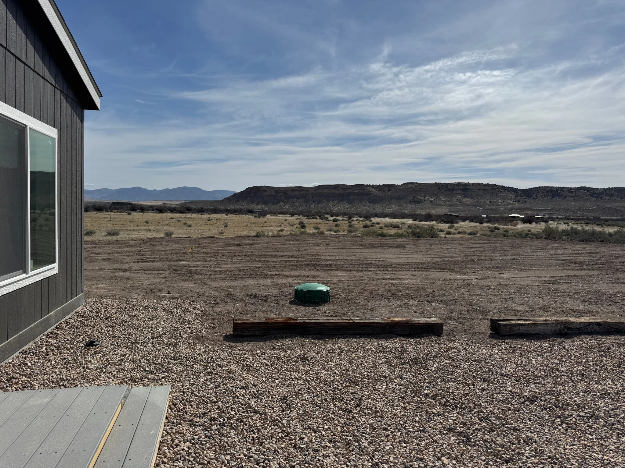 Large gravel parking area. Lid in photo shows septic tank lid access.