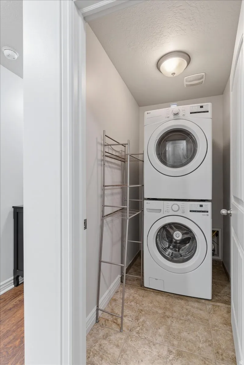 Laundry area featuring stacked washing machine and dryer and a textured ceiling