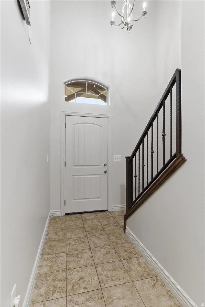 Entryway featuring a high ceiling, light tile patterned floors, and hanging lights