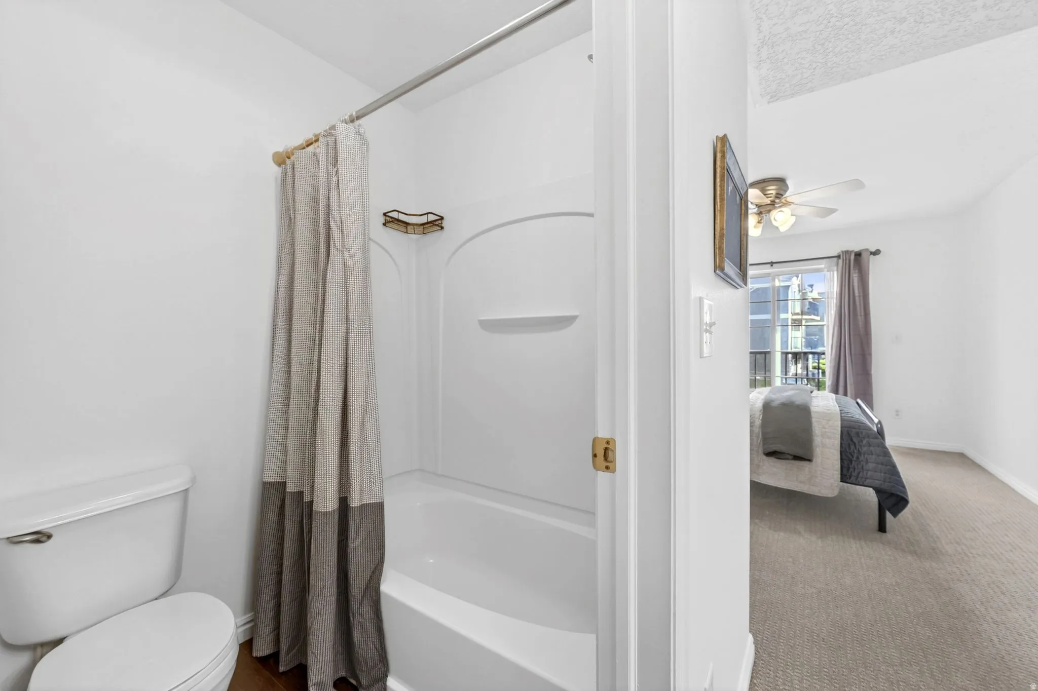 Ensuite bathroom with ceiling fan, shower / bath combination with curtain, and carpet floors