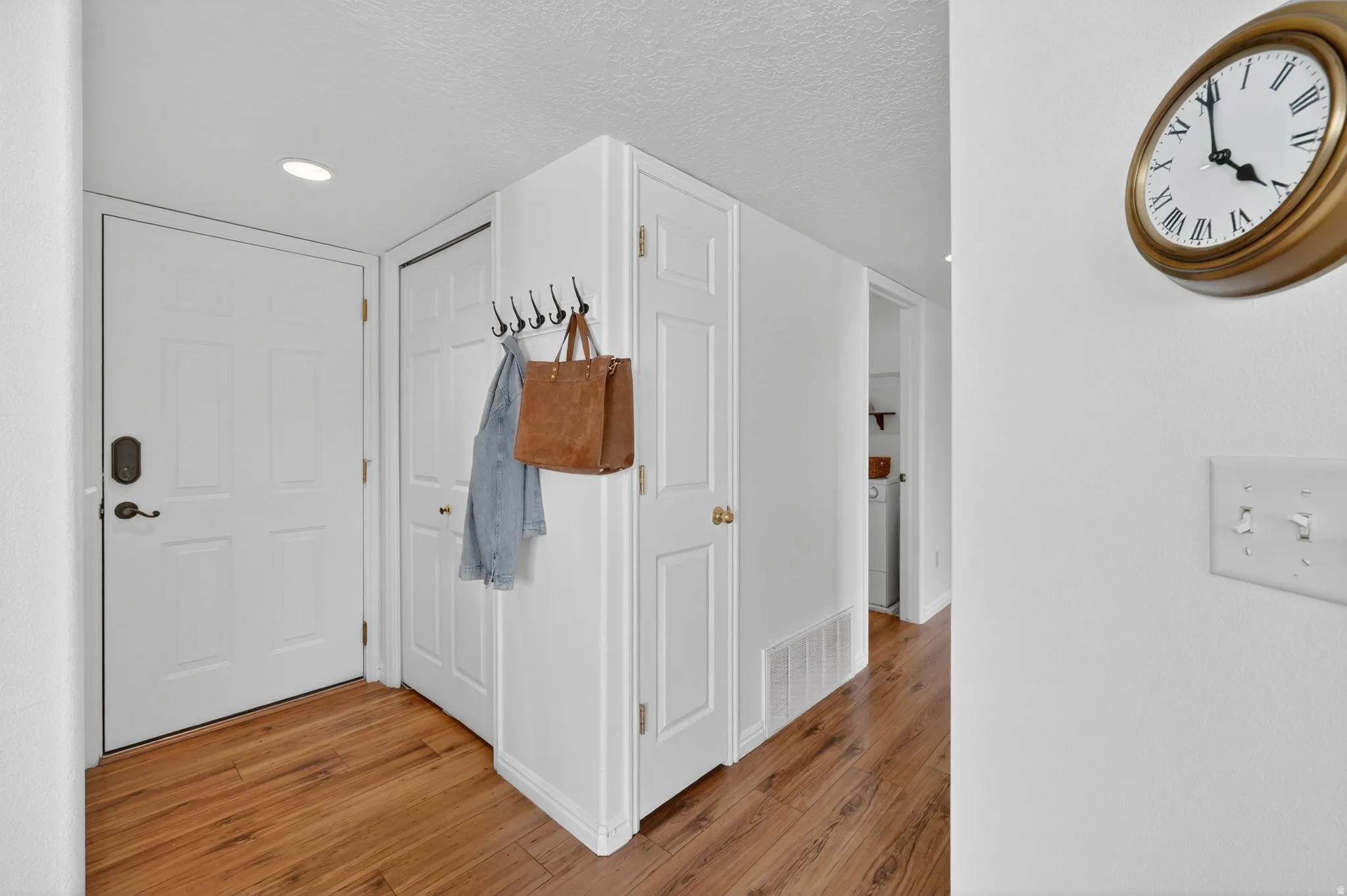 Corridor featuring light wood-style flooring, a textured ceiling, and recessed lighting