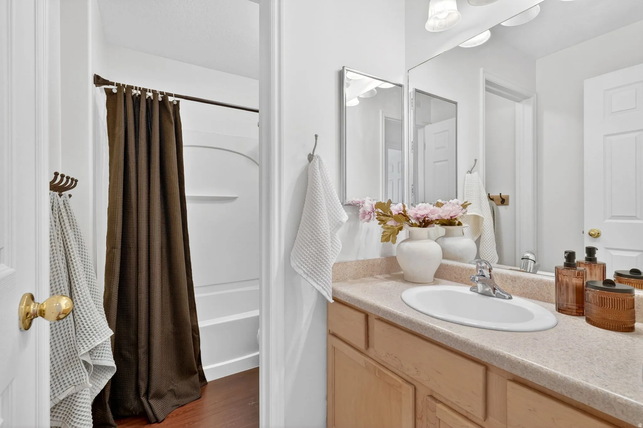 Bathroom featuring vanity, shower / tub combo with curtain, and dark wood finished floors