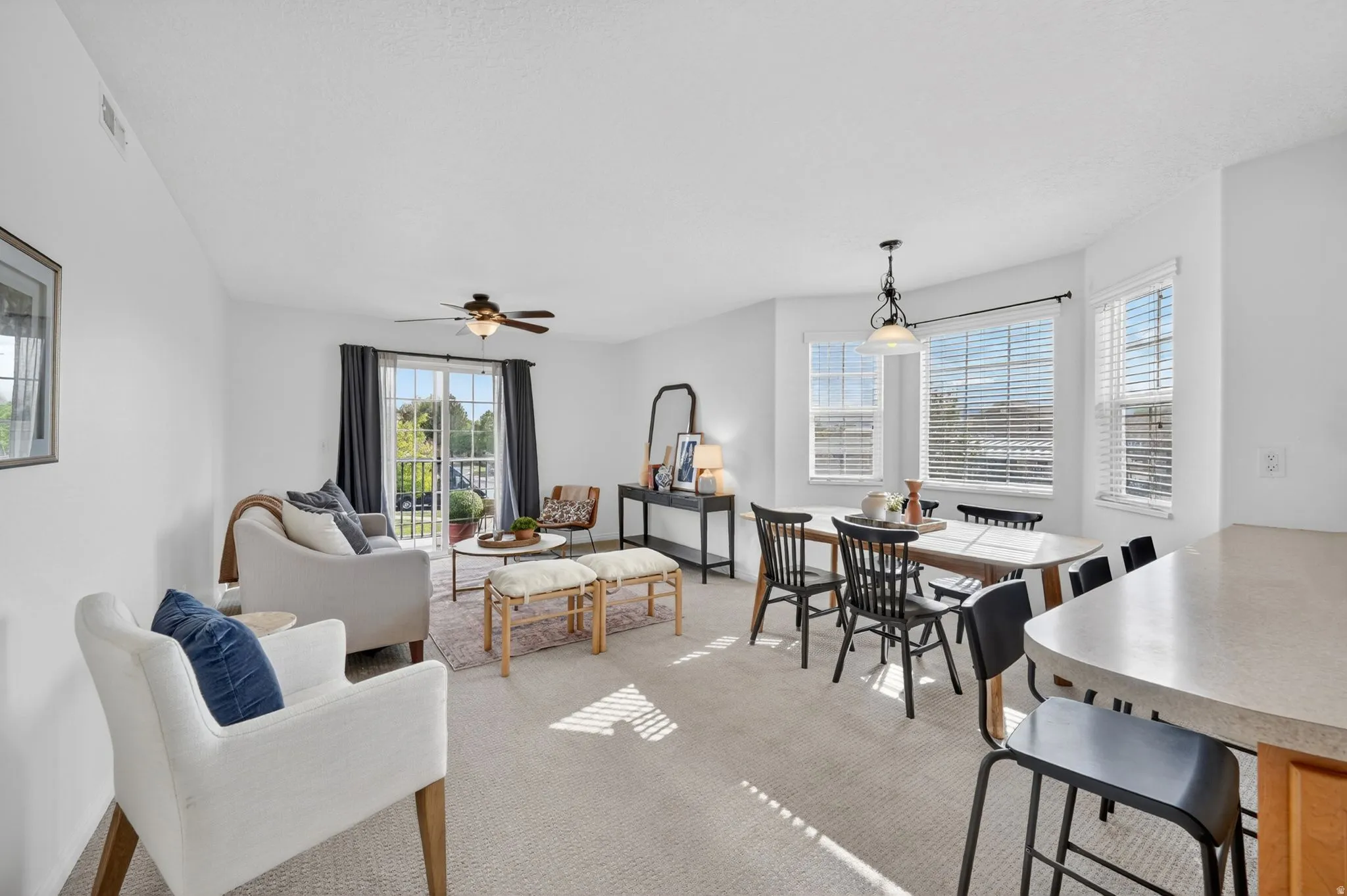 Dining space with ceiling fan and light colored carpet