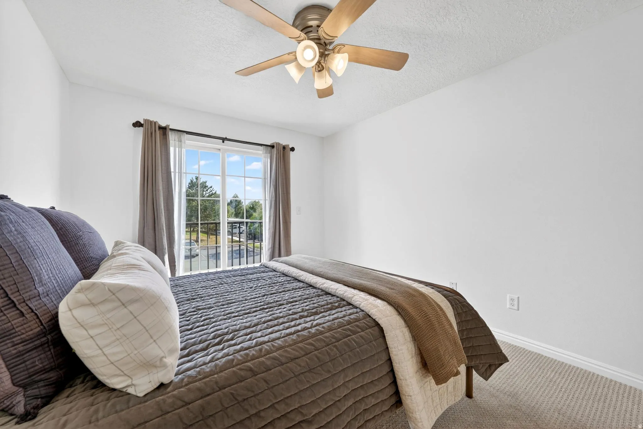 Carpeted bedroom with access to exterior, a ceiling fan, and a textured ceiling