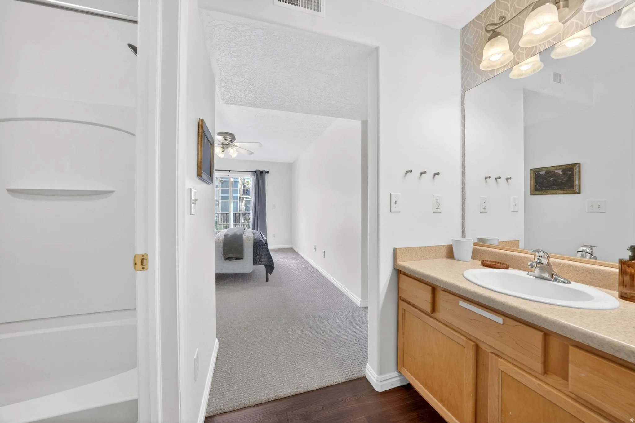 Bathroom featuring vanity, connected bathroom, dark carpet, dark wood finished floors, and bathtub / shower combination
