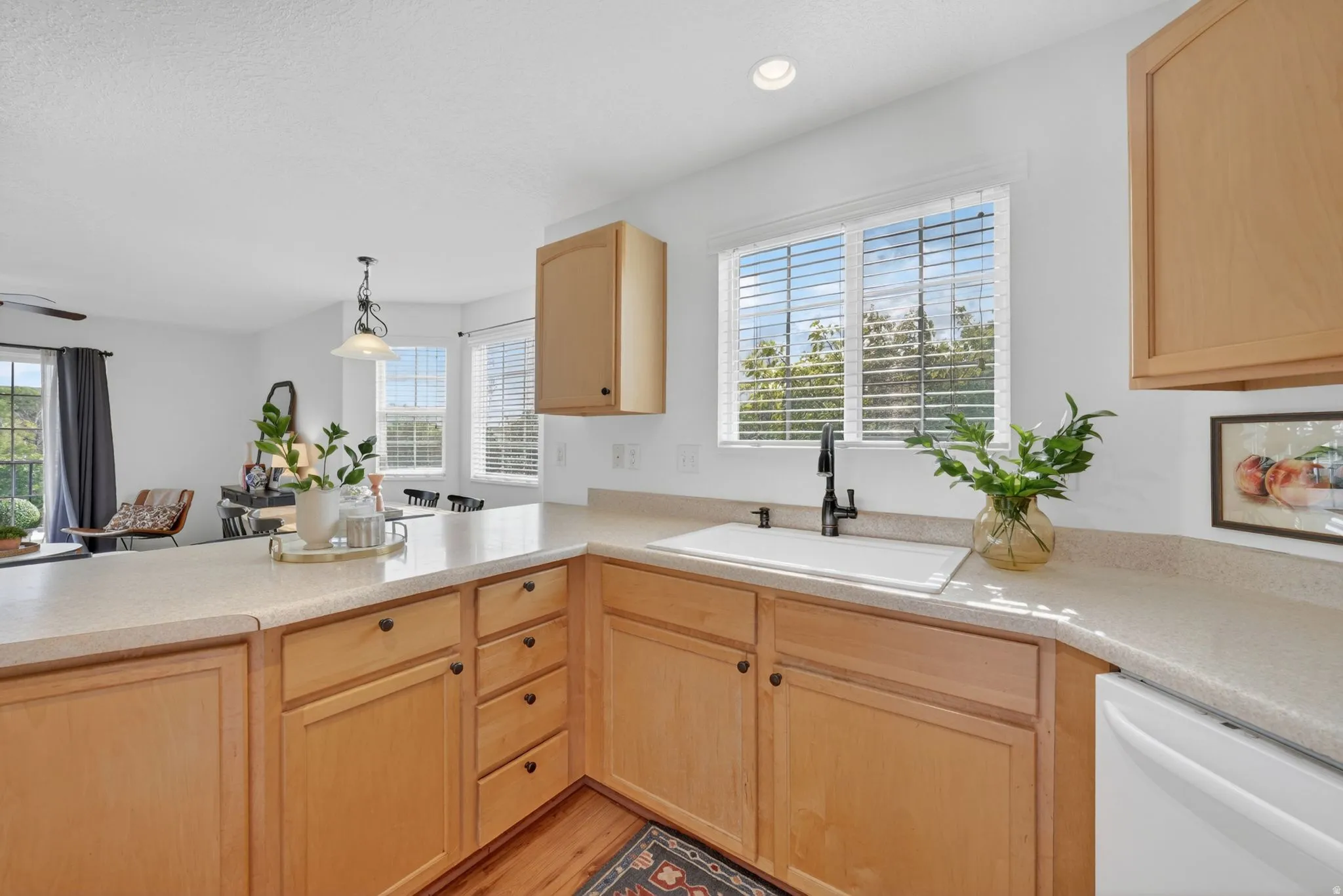Kitchen featuring light wood finish cabinetry, light countertops, hanging light fixtures, and plenty of natural light