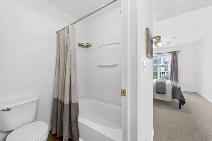Ensuite bathroom with ceiling fan, shower / bath combination with curtain, and carpet floors