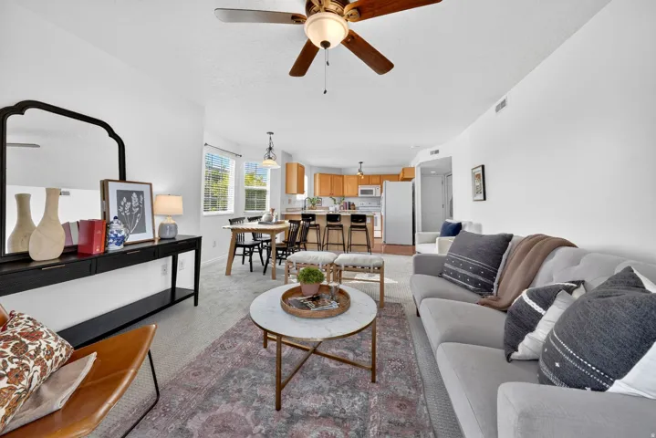 Living area featuring light colored carpet and a ceiling fan