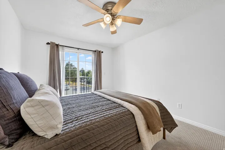 Carpeted bedroom with access to exterior, a ceiling fan, and a textured ceiling