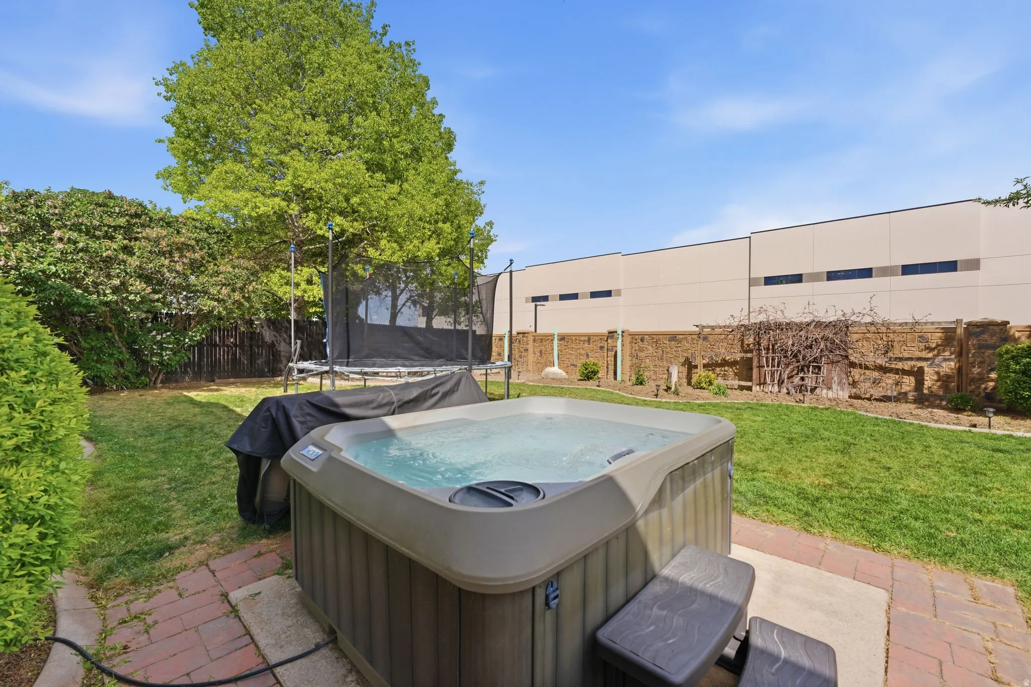 Fenced backyard with a trampoline and a patio