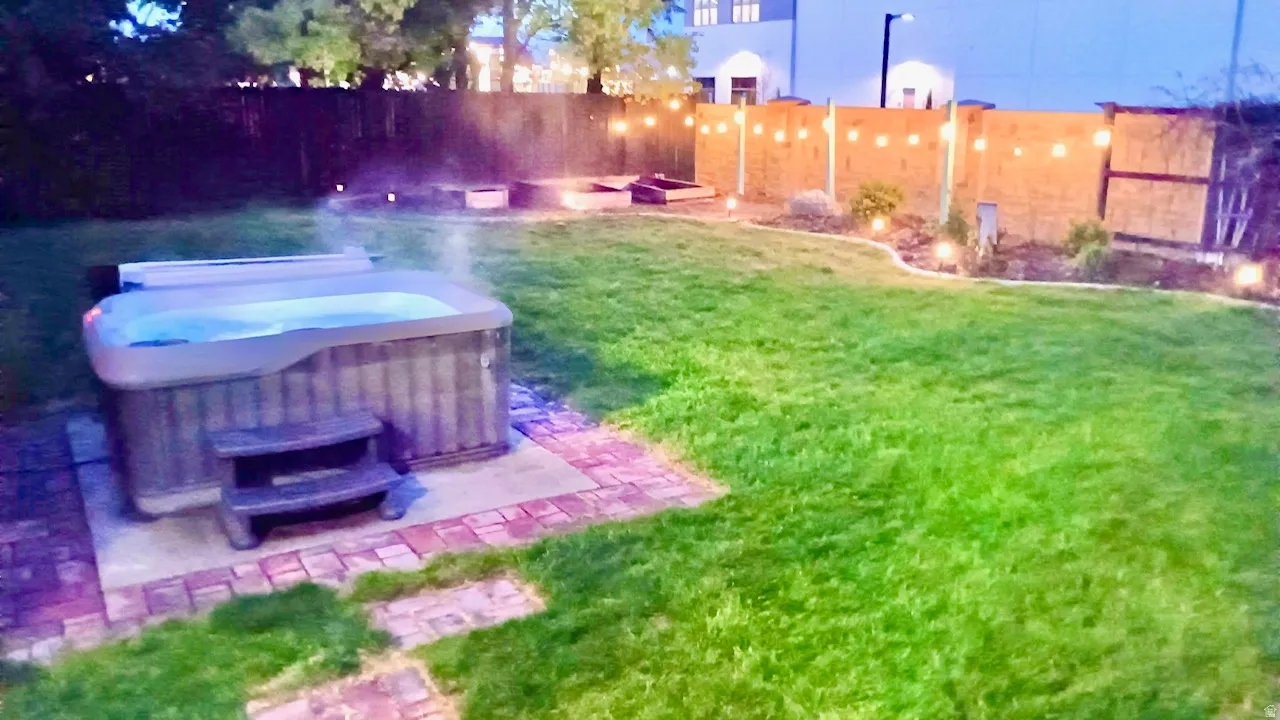 Evening View of backyard with a hot tub