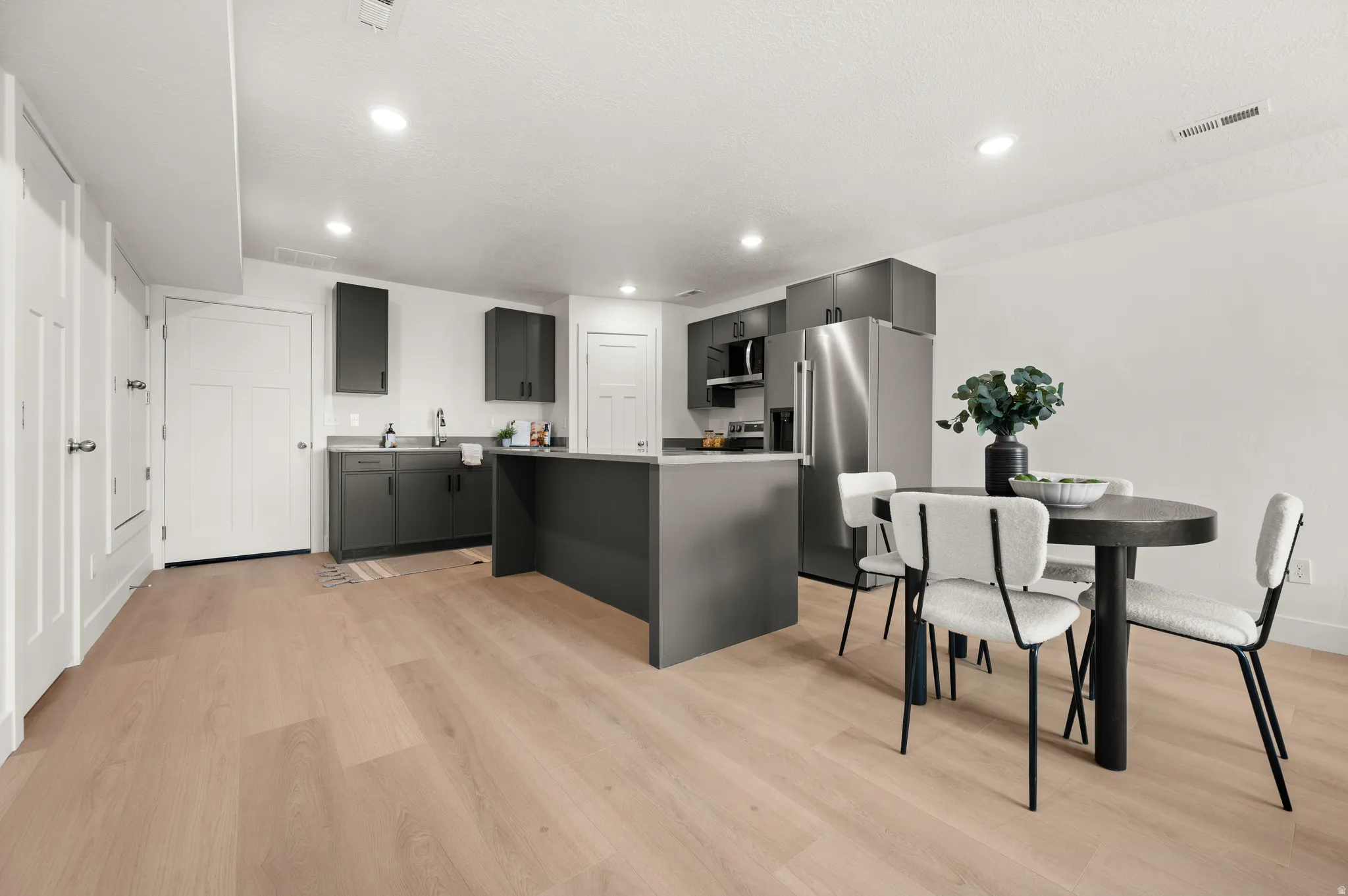 Kitchen with stainless steel appliances, a center island, light wood finished floors, light countertops, and recessed lighting