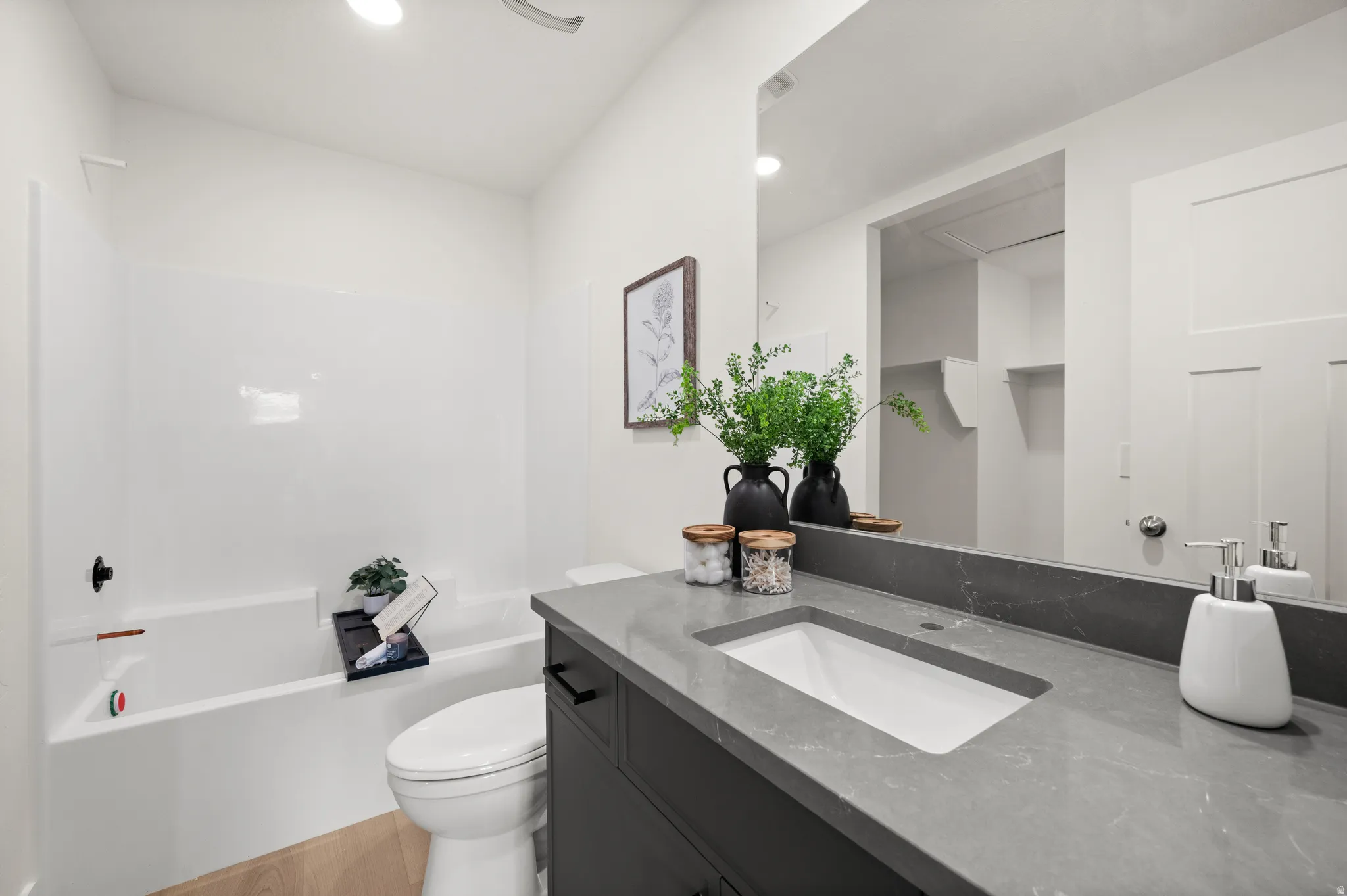 Bathroom with vanity, light wood-type flooring, shower / tub combination, and recessed lighting