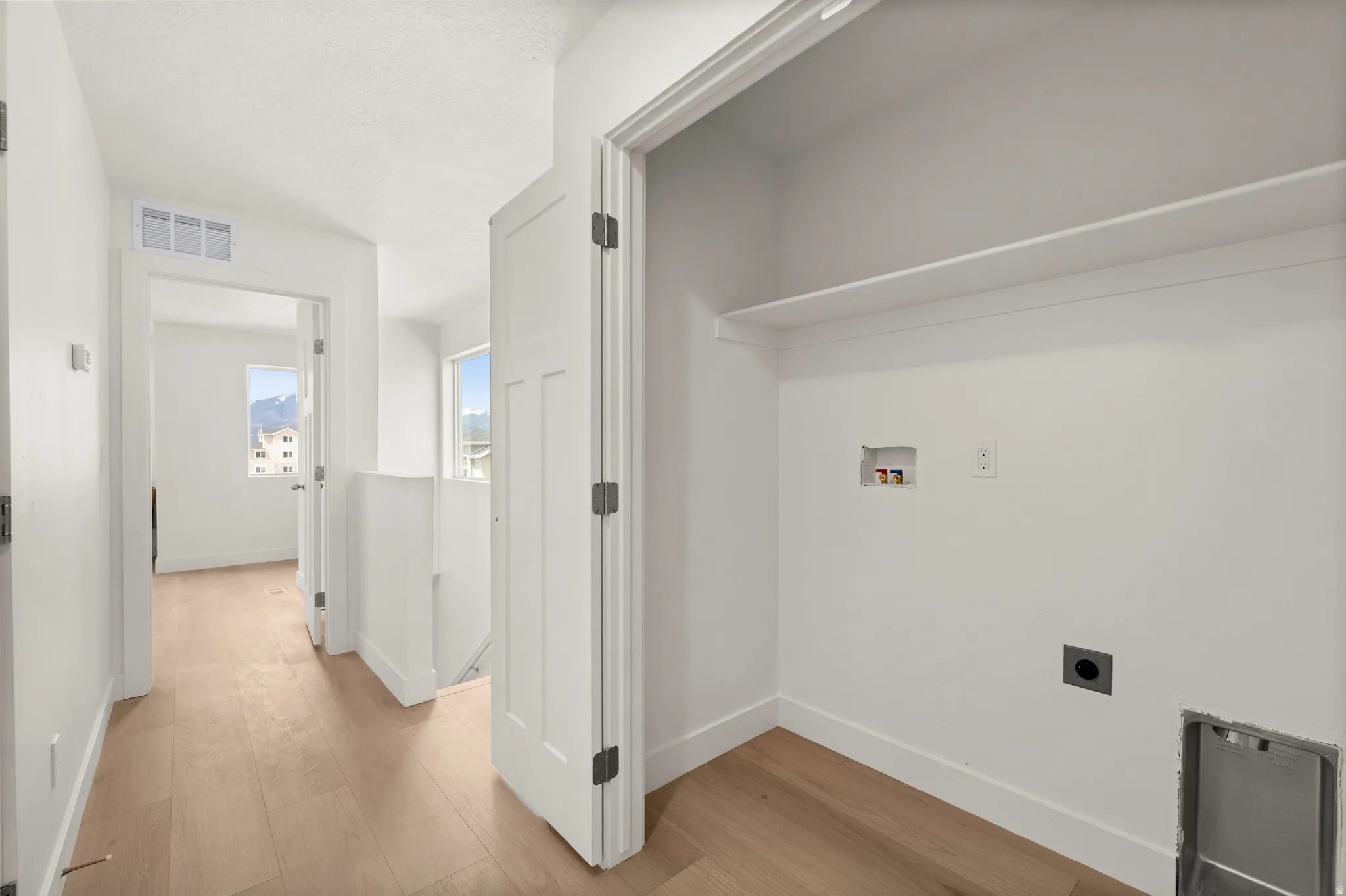 Laundry area with light wood-style floors, hookup for a washing machine, and electric dryer hookup