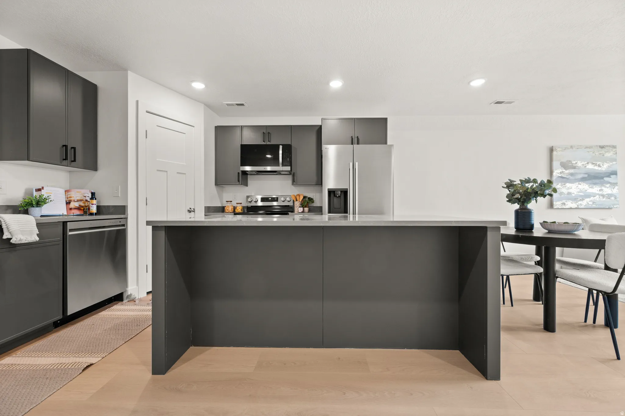 Kitchen with stainless steel appliances, a kitchen island, recessed lighting, light wood-style floors, and gray cabinets
