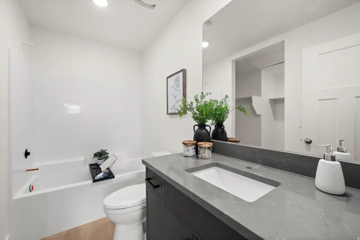 Bathroom with vanity, light wood-type flooring, shower / tub combination, and recessed lighting