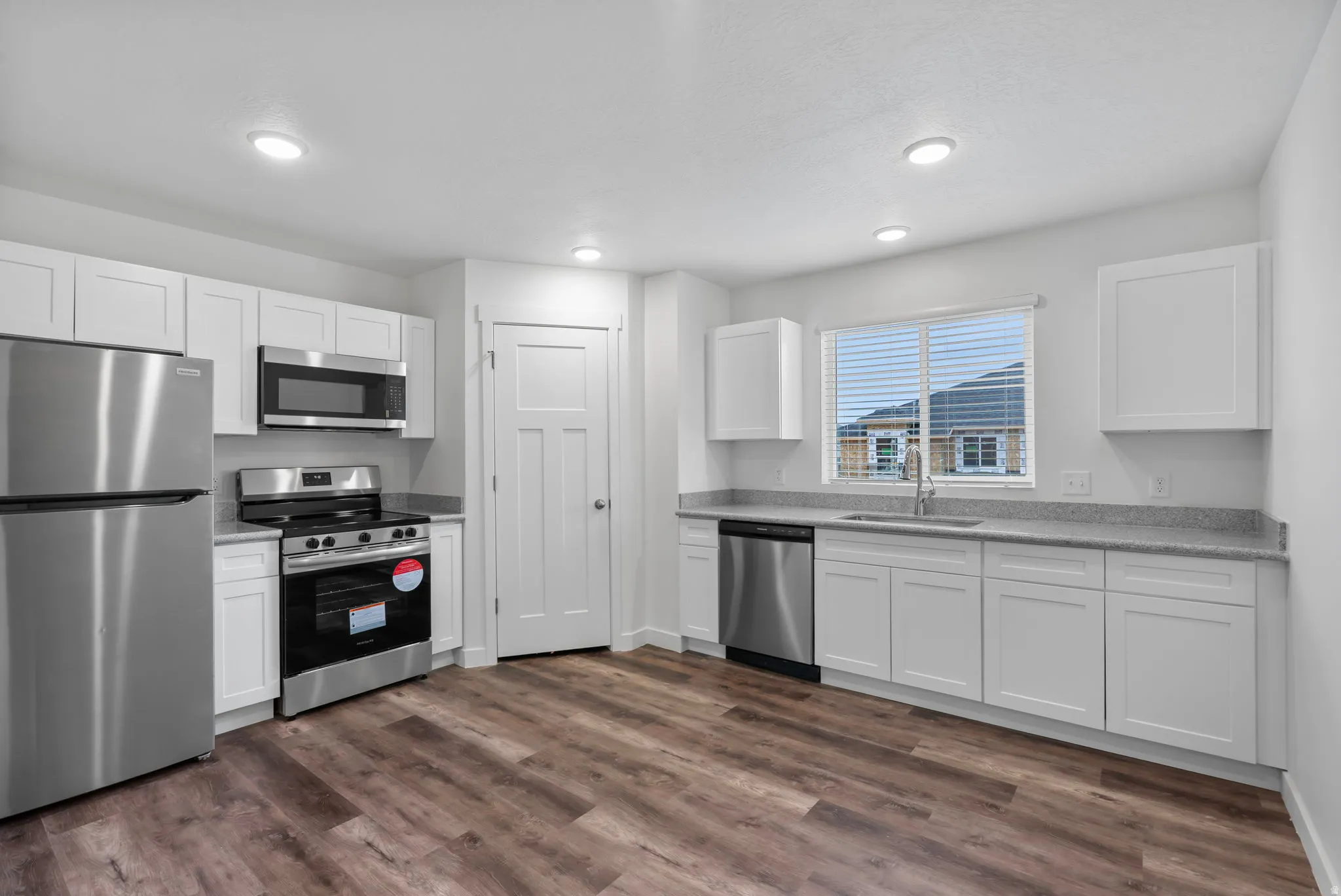 Kitchen with stainless steel appliances, white cabinetry, dark wood-style flooring, and recessed lighting