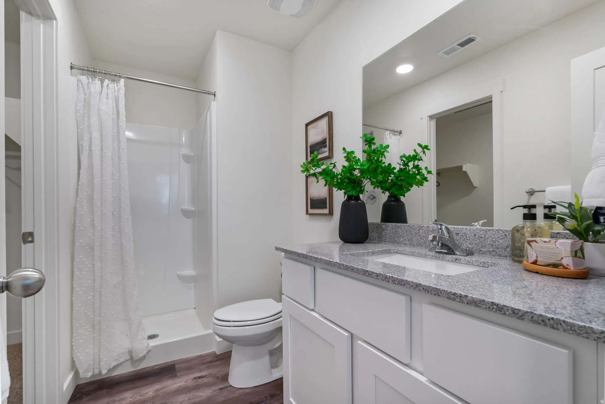 Bathroom featuring a stall shower, vanity, and dark wood-style floors