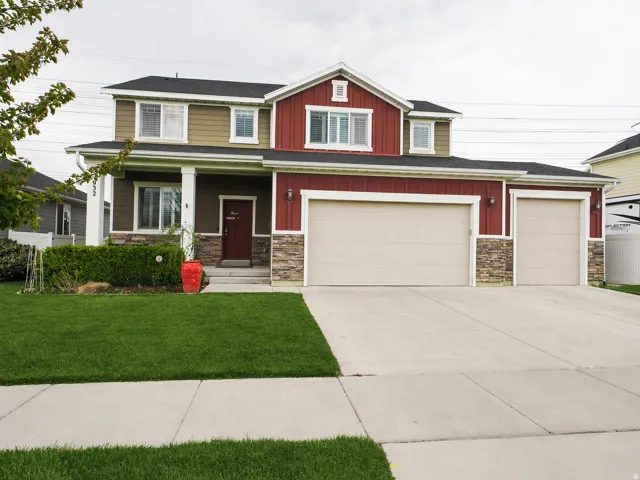 Craftsman house featuring stone siding, a porch, concrete driveway, board and batten siding, and a front lawn