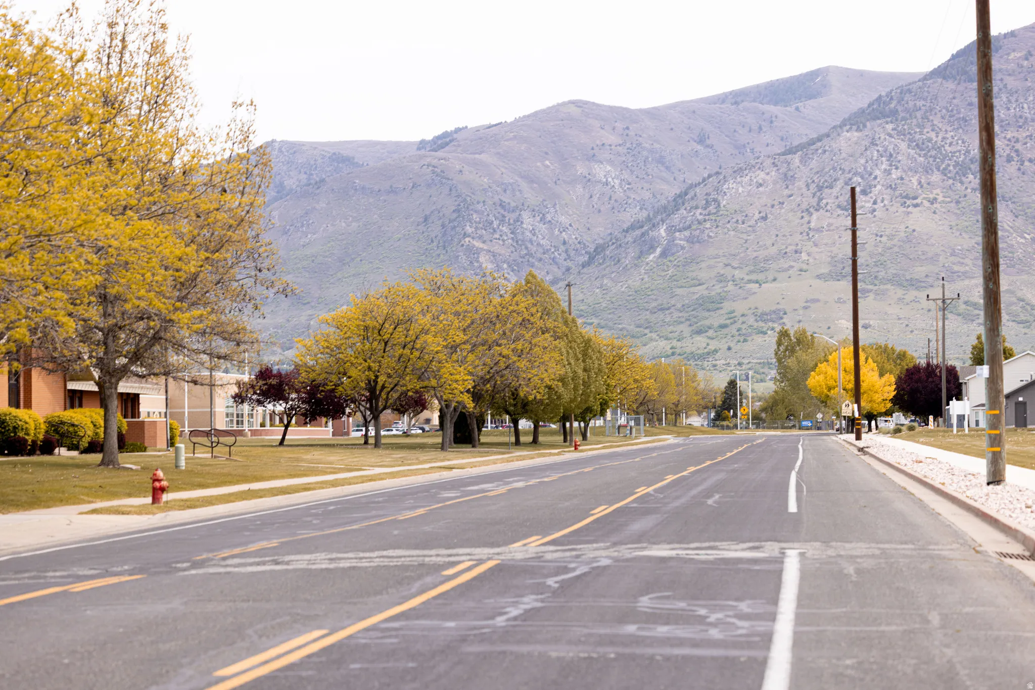 View of asphalt road with sidewalks, curbs, and a mountain view