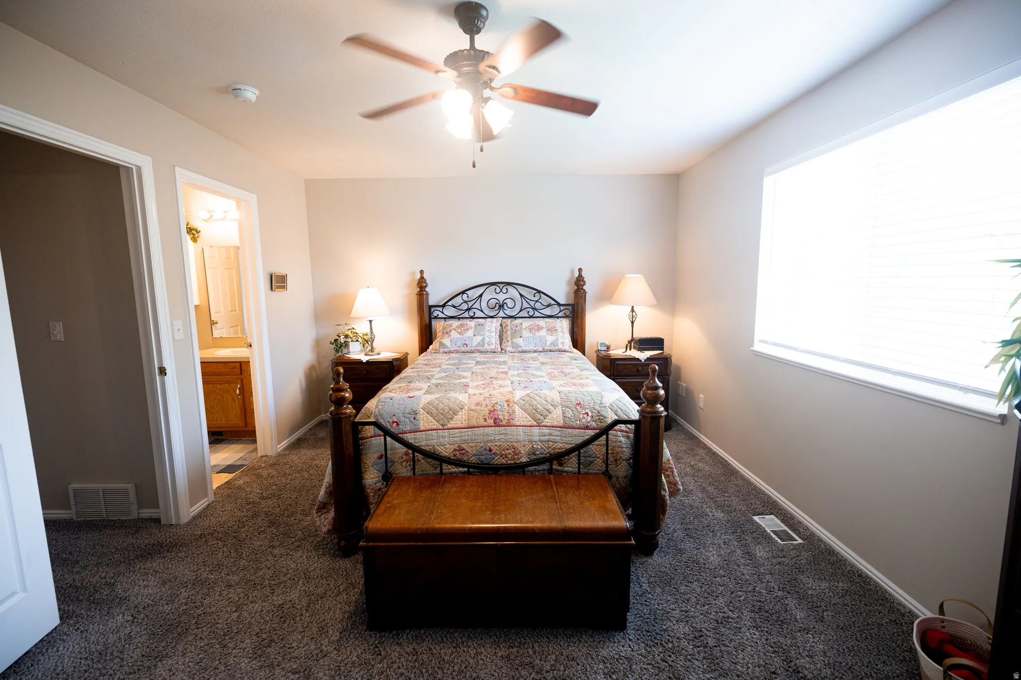 Carpeted main bedroom with ceiling fan and connected bathroom