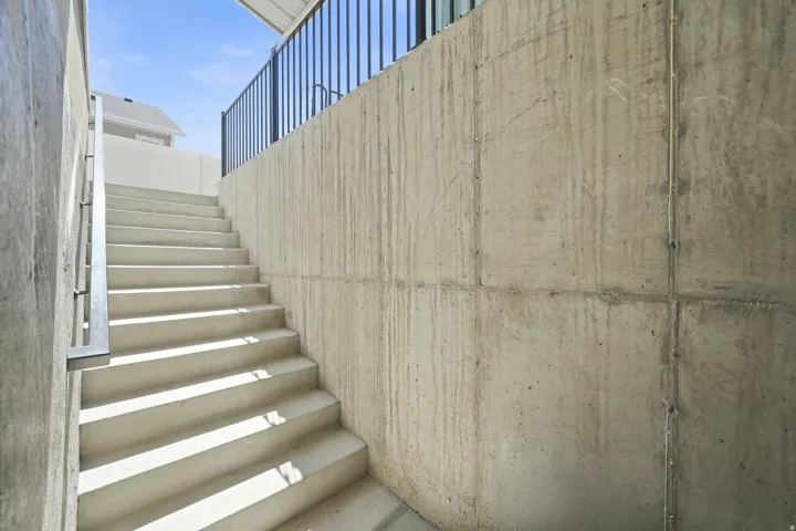 Concrete exterior stairs with a metal handrail and privacy wall