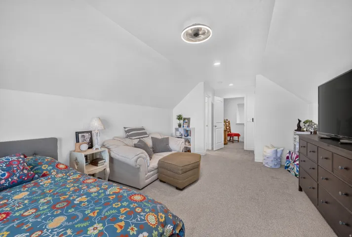 Carpeted upper-level space featuring a sloped ceiling, recessed lighting, and a modern ceiling fan