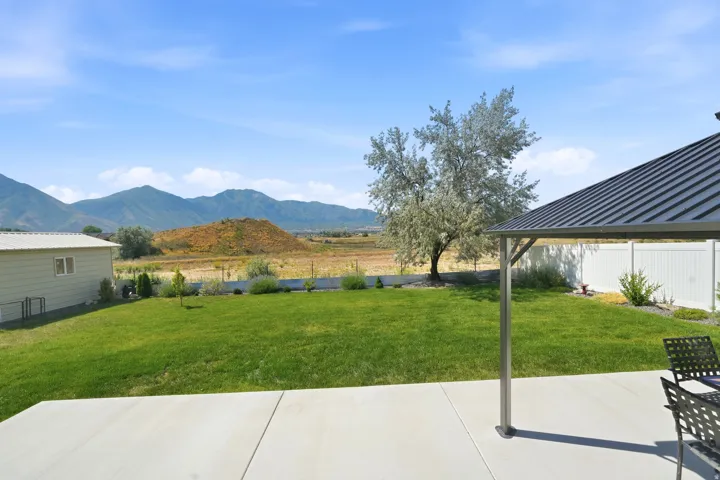 Expansive concrete patio with a covered gazebo, overlooking a large grassy yard