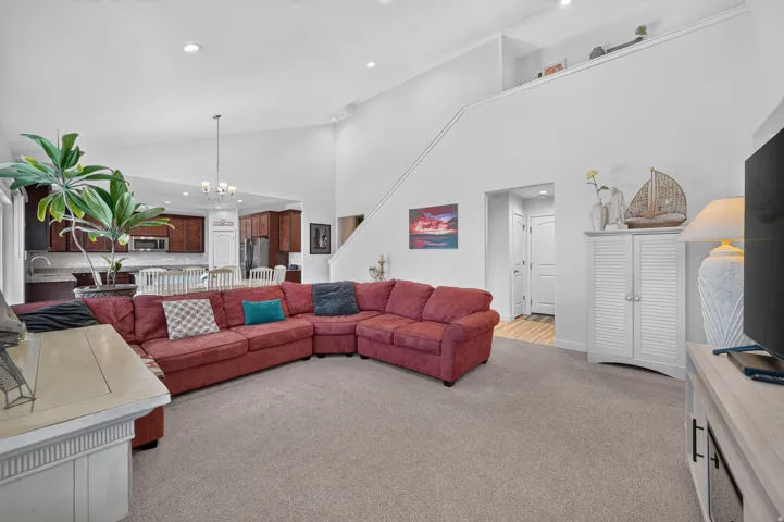 Spacious living area featuring vaulted ceilings, recessed lighting, and an open-concept design to the kitchen