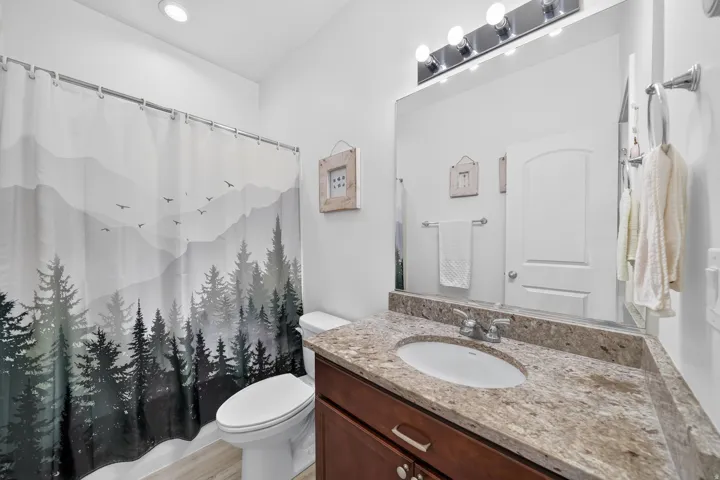 Bathroom featuring a single vanity with an integrated sink, a granite countertop, and wood-finish cabinetry