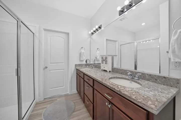 Dual vanity with granite countertop, wood-finish cabinetry, and undermount sinks