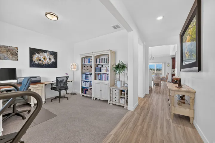 Dedicated room featuring plush gray carpeting, recessed ceiling lighting, and a built-in white cabinet with glass doors